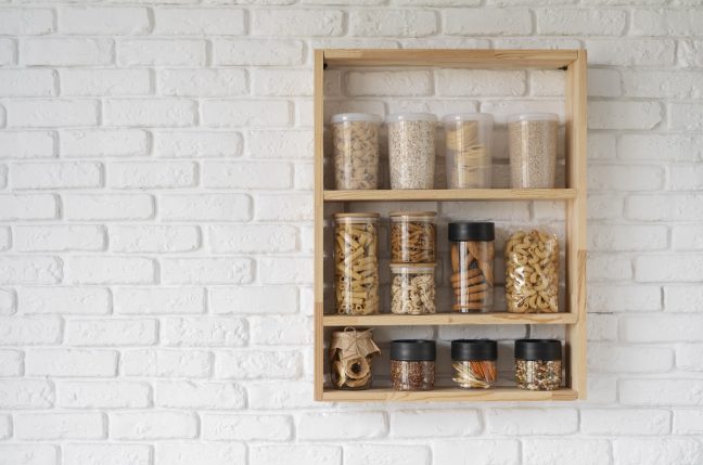 wooden rack with spices in jars mounted on a kitchen wall
