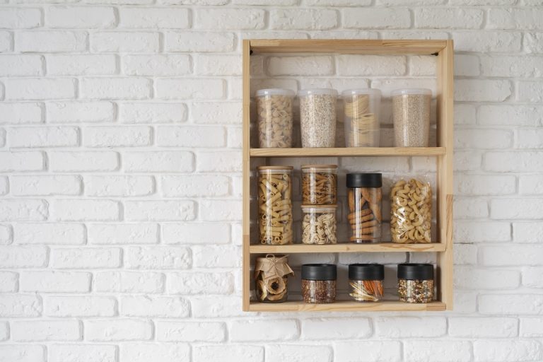 wooden rack with spices in jars mounted on a kitchen wall